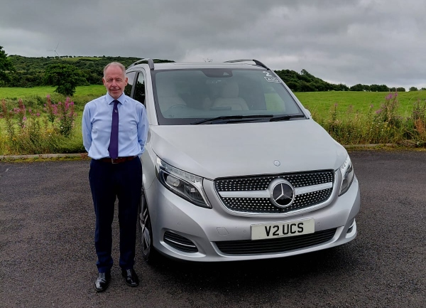 a man standing beside a car taxi tours across Ireland