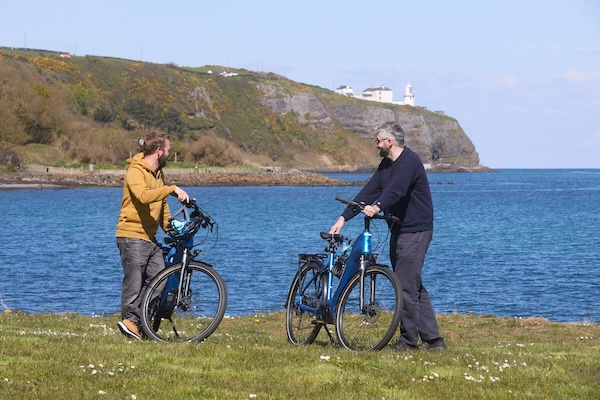 two people with bicycles on the coast 7 cool places to stay in Ireland