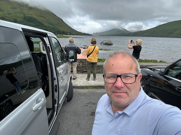 a man taking a selfie with people taking photos in the background ROC Tours
