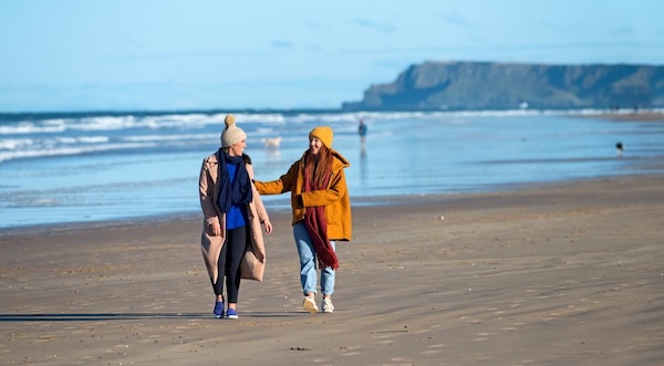 two people walking on a beach October in Ireland
