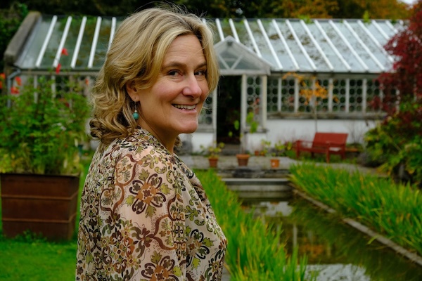 a woman standing near a greenhouse Green Door Tours