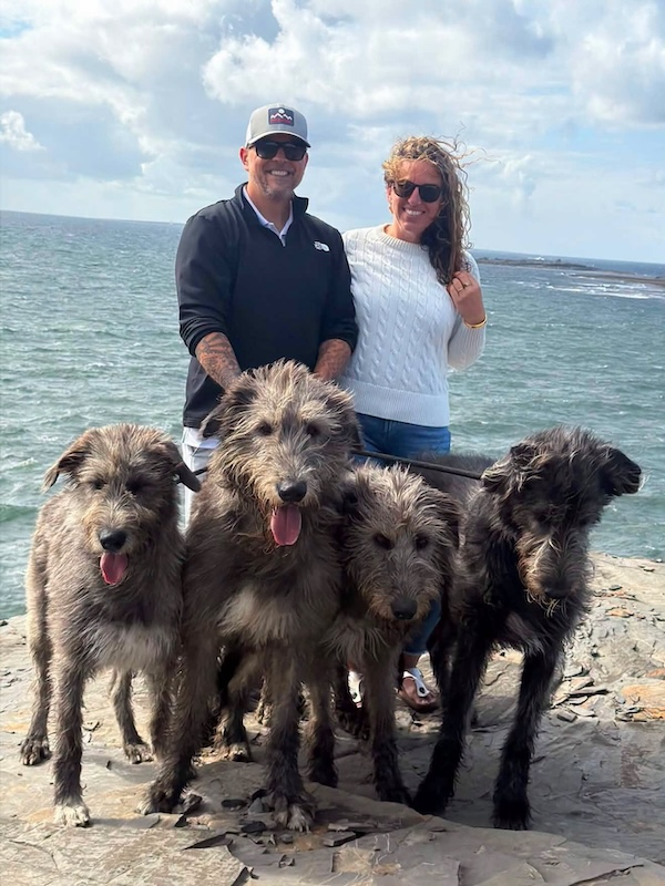 two people by the ocean pictured with wolfhounds Irish wolfhound experience in Ireland
