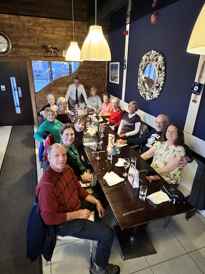 a group of people sitting at a table in a restaurant Robbie's Luxury Travel